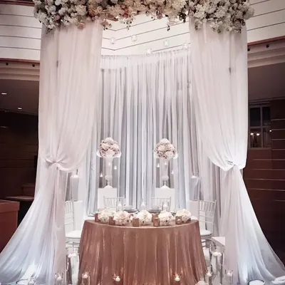 This grand, all-white decor is perfect for an elegant reception or ring ceremony. The flowing drapes and dramatic floral arch create a breathtaking canopy over the main table, exuding pure sophistication.