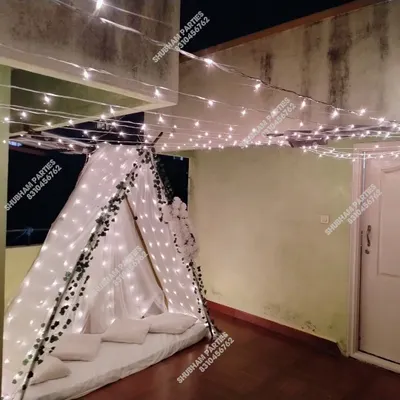 A cozy and romantic cabana tent setup on a balcony, decorated with fairy lights and ivy, perfect for a surprise date night.