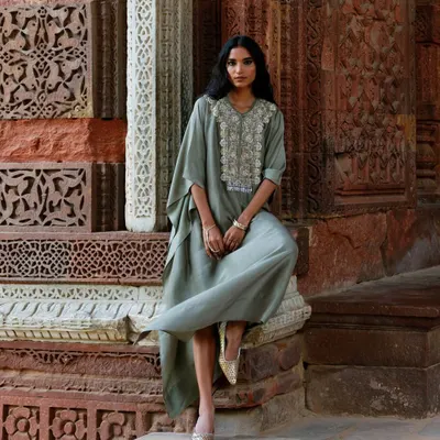 The beauty of a timeless silhouette against a historic backdrop. This model wears a sage green kaftan with an embroidered yoke, a perfect blend of comfort and elegance.