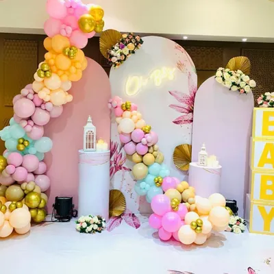 A bright and colorful baby shower backdrop featuring a mix of pastel balloons, an "Oh Baby" neon sign, and floral graphic panels. We also included white plinths for desserts and large "BABY" letter blocks as props.