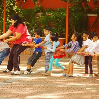 Even the teachers join in on the fun! A game of tug-of-war becomes a whole-class activity, building a sense of community and showing kids that adults can play too.