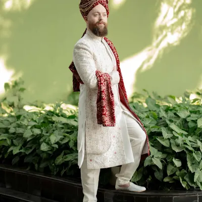 A strong and stylish portrait of the groom in his wedding sherwani. The confident pose and clean background highlight his regal attire and readiness for the big day.