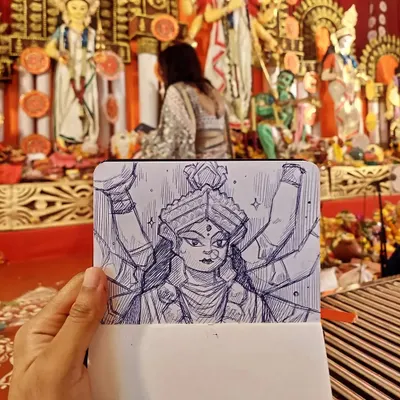 Holding up my sketch of the goddess Durga against the backdrop of the actual idol at a Durga Pooja pandal. My aim with these live drawings is to capture the divine presence and intricate details of the idols in my own expressive style.