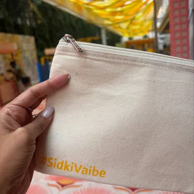 A close-up of a blank pouch being personalized with the custom #SidkiVaibe hashtag for a Haldi party. This first stamp is the beginning of a unique creation that guests will treasure as a memory of the special day.