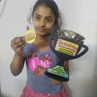 A proud winner showing off her second-position trophy and medal for the national level poetry and storytelling contest.