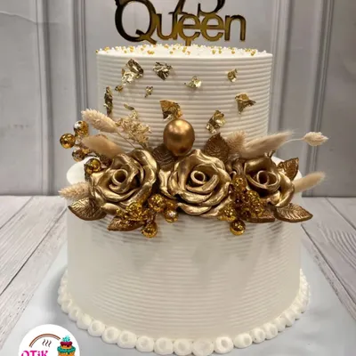 We designed this stunning two-tiered cake to celebrate a 75th birthday. The clean white buttercream is adorned with beautiful golden roses and a "75 Queen" topper, making it a truly regal centerpiece.