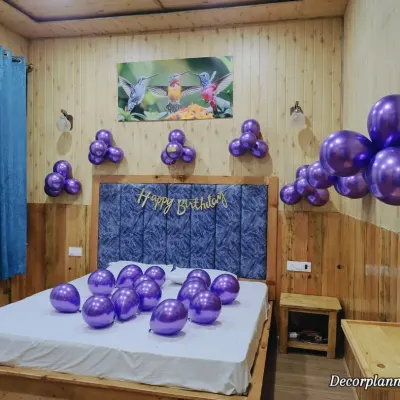 Sometimes, simplicity is key. This basic room decor features clusters of metallic purple balloons on the wall and scattered on the bed, with a simple 'Happy Birthday' banner. It's an easy and affordable way to create a surprise.