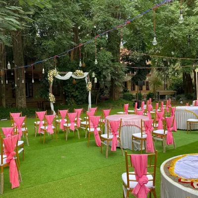 A beautiful daytime wedding reception setup at UTC. The vibrant pink sashes on the chairs add a pop of color to the lush green lawn, while the wooden arch creates a perfect focal point for the ceremony.