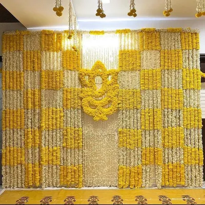 For a Haldi ceremony at home, I designed this full feature wall using a checkerboard pattern of yellow and white marigolds. The centerpiece is a Ganesha motif made entirely of fresh yellow marigold flowers, making it a perfect photo backdrop.