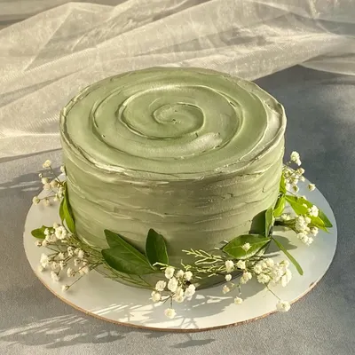 I love the simple beauty of this sage green cake. The rustic, textured frosting is complemented by a delicate wreath of baby's breath and leaves, creating a natural and modern look.