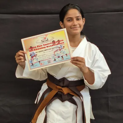A student proudly holds her certificate after successfully passing her belt exam. This marks her one step closer to achieving her black belt.