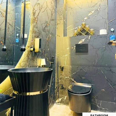 A luxurious bathroom design featuring black marble walls with gold veining, a modern black pedestal sink, and dramatic pendant lighting that creates a bold and sophisticated statement.