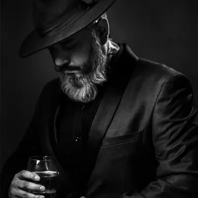 This black and white portrait uses a classic lighting technique to create a moody, cinematic feel. The fedora and suit add to the character, making it a strong addition to any actor's portfolio.