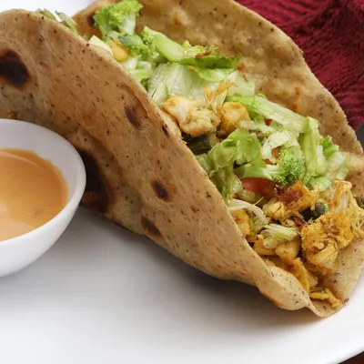 A close-up of a freshly prepared chicken and vegetable wrap, showcasing crisp lettuce and tender ingredients. This style of food photography is ideal for menu displays and promotional content for cafes and takeaways.
