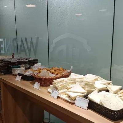 A high-tea spread for Warner Bros Discovery, featuring classic sandwiches, savory bites in wicker baskets, and desserts. Perfect for casual meetings or corporate mixers.