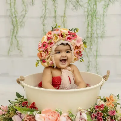 Cuteness overloaded! A six-month-old baby girl having a blast in a bathtub splash session, complete with a beautiful floral bonnet.