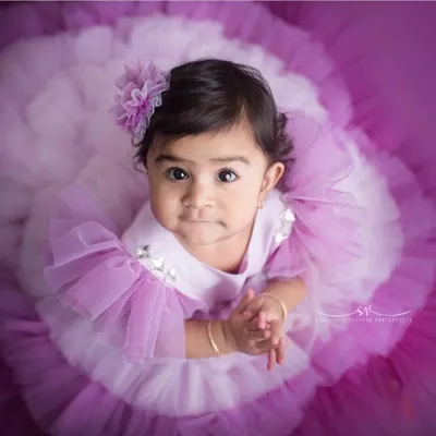 This little one came to slay. This custom lavender gown with its dramatic ruffled tulle skirt and matching floral hairpiece is designed for maximum impact, ensuring your baby is the center of attention at her milestone celebration.