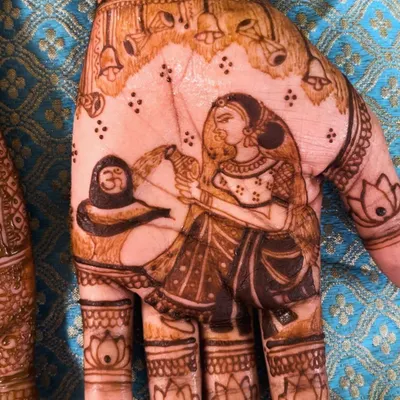 A close-up of a divine Shiva-Parvati portrait on the palm. This is a beautiful way to incorporate spiritual elements into your bridal henna.