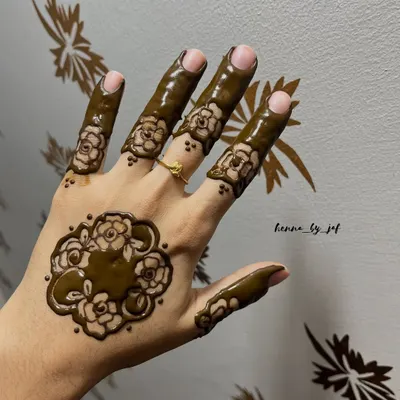 A modern floral design featuring a single large motif on the back of the hand. The fingers are decorated with matching floral bands, creating a bold yet uncluttered look.