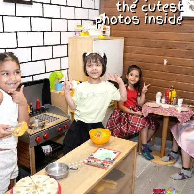 Girls having a blast in the pretend-play kitchen during a Frozen-themed party.