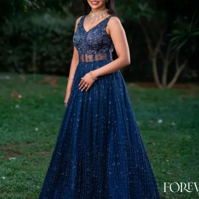 This full-length view showcases the dazzling effect of the blue katdana corset gown. The intricate beadwork covers the entire gown, creating a sparkling texture that catches the light beautifully, perfect for a reception or gala.