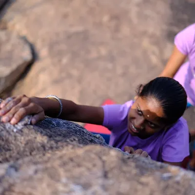 A close-up of a young climber getting her first feel of real rock, with an instructor providing gentle guidance. Our outreach events focus on making outdoor climbing accessible.
