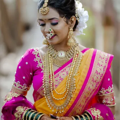 A classic Maharashtrian bridal portrait. We created a look that highlights her beautiful features, complete with traditional gold jewelry, a floral bun, and the iconic crescent bindi.