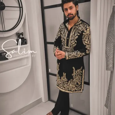 A client wearing a black velvet kurta with heavy gold and silver floral embroidery. This is a luxurious and statement-making piece, perfect for a grand celebration or reception.