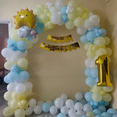 A cheerful sun-themed first birthday decoration. This simple balloon arch in pastel yellow and blue is perfect for a small home celebration.