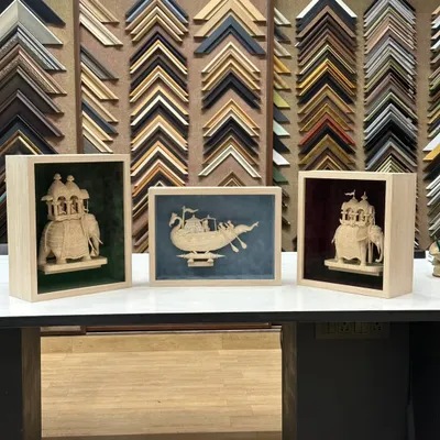 A look at the completed Sholapith art pieces, each in its own custom shadow box. The light maple wood frames and distinct suede backgrounds were chosen to complement the individual character of the boat and elephant sculptures.