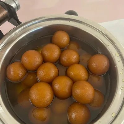 A pot of warm, syrupy Gulab Jamuns. This classic Indian dessert is a sweet and satisfying end to any meal.