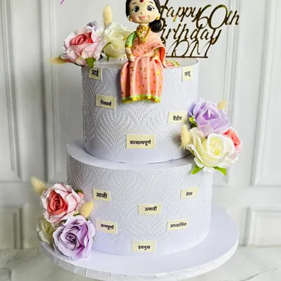 Celebrating 60 graceful years with this custom two-tier cake. It features a beautiful fondant figurine of a mother in a traditional saree, surrounded by words that describe her loving nature.