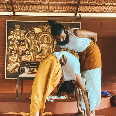True progress in yoga comes from discipline and patient guidance. I am assisting a student in a deep forward bend, helping them find their edge safely while respecting the body's limits.