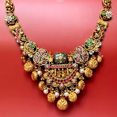 This temple style gold necklace is a tribute to tradition. It features intricate nakshi craftsmanship, uncut diamonds, pearls, and rich enamel detailing, making it a perfect heirloom for the modern woman who cherishes her roots.