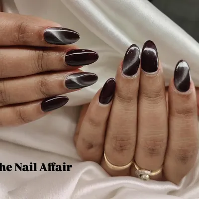 A dramatic and moody cat eye effect on dark, almond-shaped nails. The magnetic polish creates a stunning silver streak that shifts in the light.