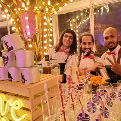 My team and I, dressed in bow ties, are ready to serve at the 'London Calling' themed bar. We bring a fun and professional vibe, ensuring your guests have a brilliant time.