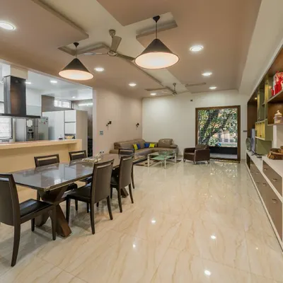 An open-concept living and dining area in a large Bangalore residence. The polished marble floors and neutral color palette create a bright, expansive feel, while the layout ensures a practical flow between the kitchen, dining, and lounge zones.