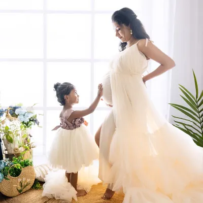 A beautiful moment between a mother-to-be and her daughter. The little girl gently touches her mom's baby bump, excited to become a big sister. A perfect way to capture this special time for the whole family.