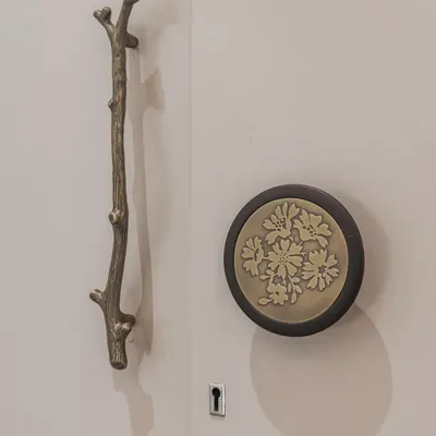 A close-up of the unique hardware chosen for our "Mother of Pearl" wardrobe. The branch-like handle and floral-embossed knob are artistic details that elevate the entire piece.
