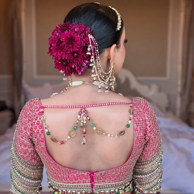 A bold floral statement for a beautiful bride. This large, vibrant magenta floral arrangement sits perfectly on a classic sleek bun, creating a breathtaking look for a day wedding. The style is both traditional and incredibly striking.