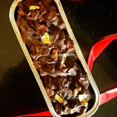 A close up of my vanilla loaf cake, which is soaked with flavor and generously topped with dark chocolate ganache, fresh strawberries, and a touch of edible gold leaf for a little luxury. This is a truly decadent individual dessert.