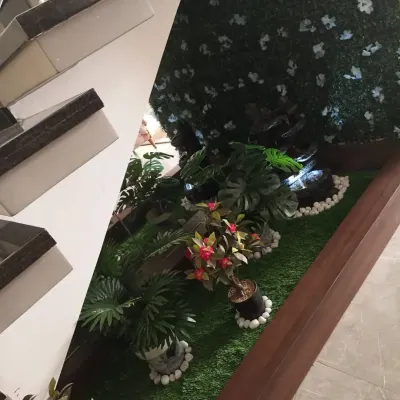 I transformed the unused space under a modern staircase into a small indoor garden. The project included artificial grass, a vertical plant wall, and decorative potted plants.