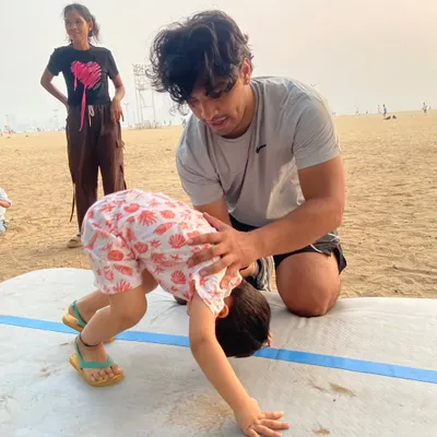Our coaches are experts at making fitness fun, even at birthday parties! Here, a coach provides hands-on assistance as a child learns a new move on an air mat during a celebration.