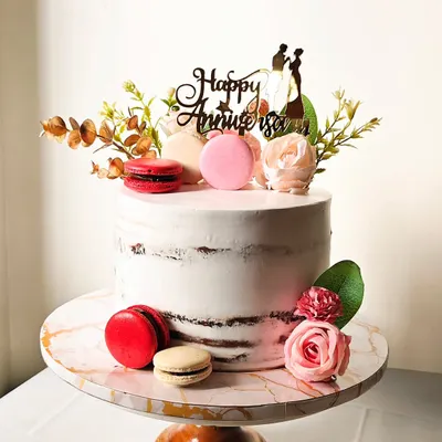 I love the rustic charm of a semi-naked cake. This anniversary cake is decorated with fresh flowers and colorful macarons, allowing the texture of the cake to peek through for a simple yet sophisticated look.