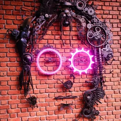 A different view of our John Lennon junk art portrait. Every piece of scrap, from chains to cogs, was carefully selected and welded to build the texture and form of his face, with neon glasses adding a modern twist.