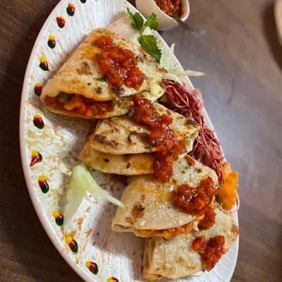 A closer look at my freshly made Veggie Quesadillas. They are filled with grilled vegetables and melted cheese, served on a decorated platter with a side of tangy salsa.