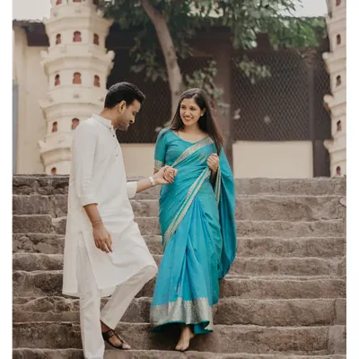 A candid moment of the couple descending the historic stone steps at Banganga, showcasing the beautiful drape of the turquoise saree.