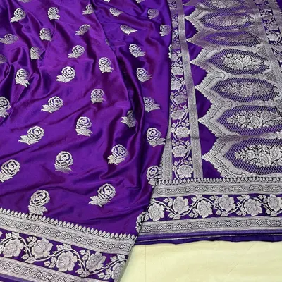 This royal purple Banarasi Mashru silk saree features an intricately woven silver border and delicate rose butis all over. The pallu has a traditional heavy design, making it a statement piece.