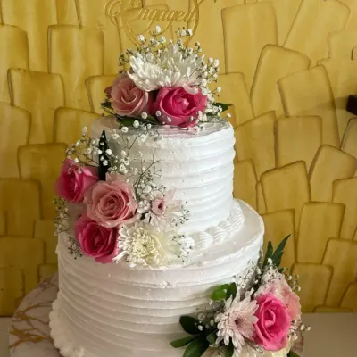 A classic two-tiered engagement cake with white ridged buttercream. I decorated it with a cascade of fresh pink and white roses and baby's breath for a touch of natural beauty and romance.