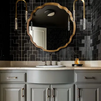 An atmospheric powder room featuring the 'Fretwork' collection from Phillip Jeffries. The elaborate geometric pattern in a bold charcoal shade adds a layer of moody sophistication and intricate detail to the space.